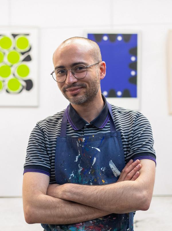 Pierre Verdon pose souriant avec son tablier constellé de peintures. Le fondateur de l'atelier de sérigraphie à Rezé, Atelier Parades est ouvert à de multiples propositions. Il réalise des textiles uniques imprimés à la main et tissés en France, du papier peint, des décors de théâtre, des affiches, de la papeterie, de la pièce unique à la petite série.