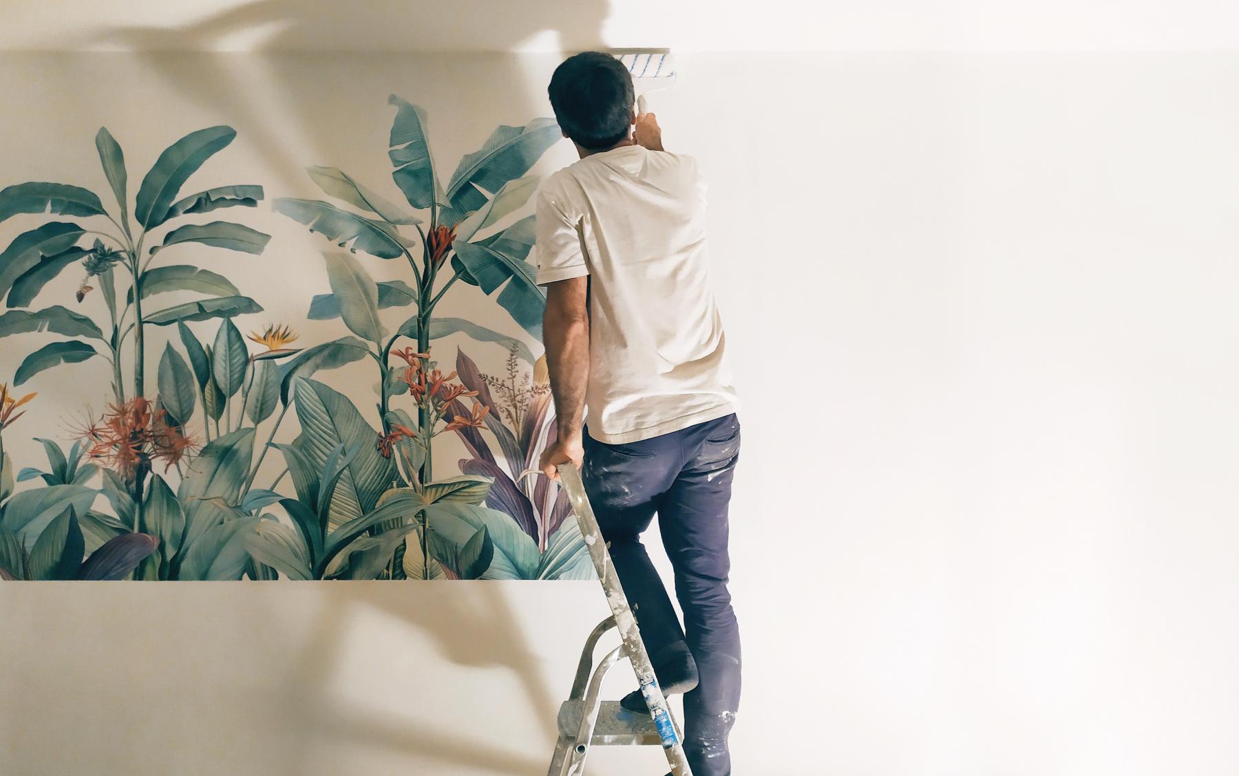 Jérôme Barrier pose la fresque végétale en papier sur le mur du cabinet paramédical.