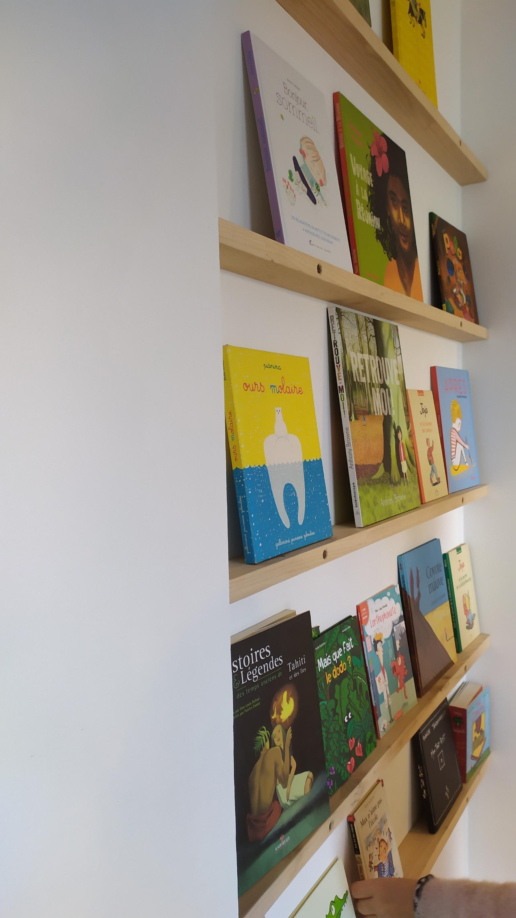 Des livres sont posés face couverture sur des étagères fines réalisés dans le parquet en chataigner. Idée originale de Jérôme Barrier.