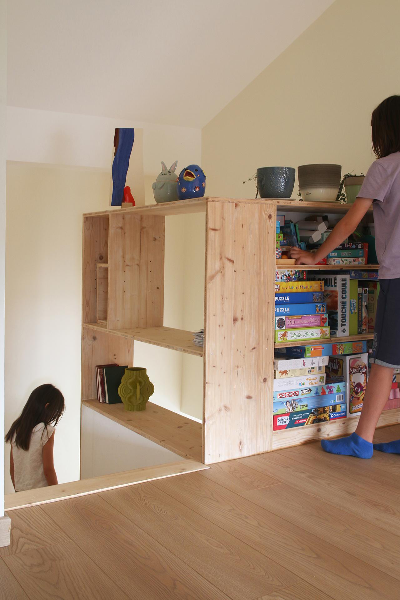 Vu de l'escalier bibliothèque sur le pallier du haut avec des rangements en bois. Design Jérôme Barrier Vertou