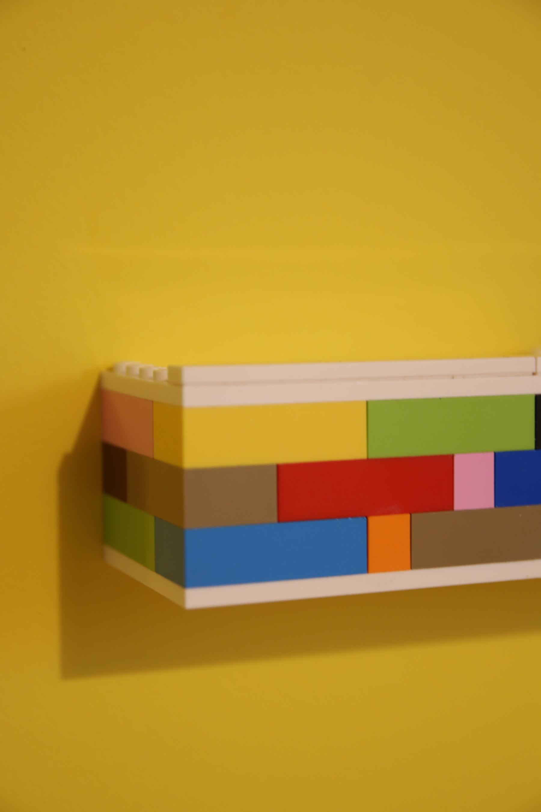 Détail d'une étagère en bois habillée avec des Lego. Dimensions flexibles et customisables à souhait. Réalisation Jérôme Barrier.