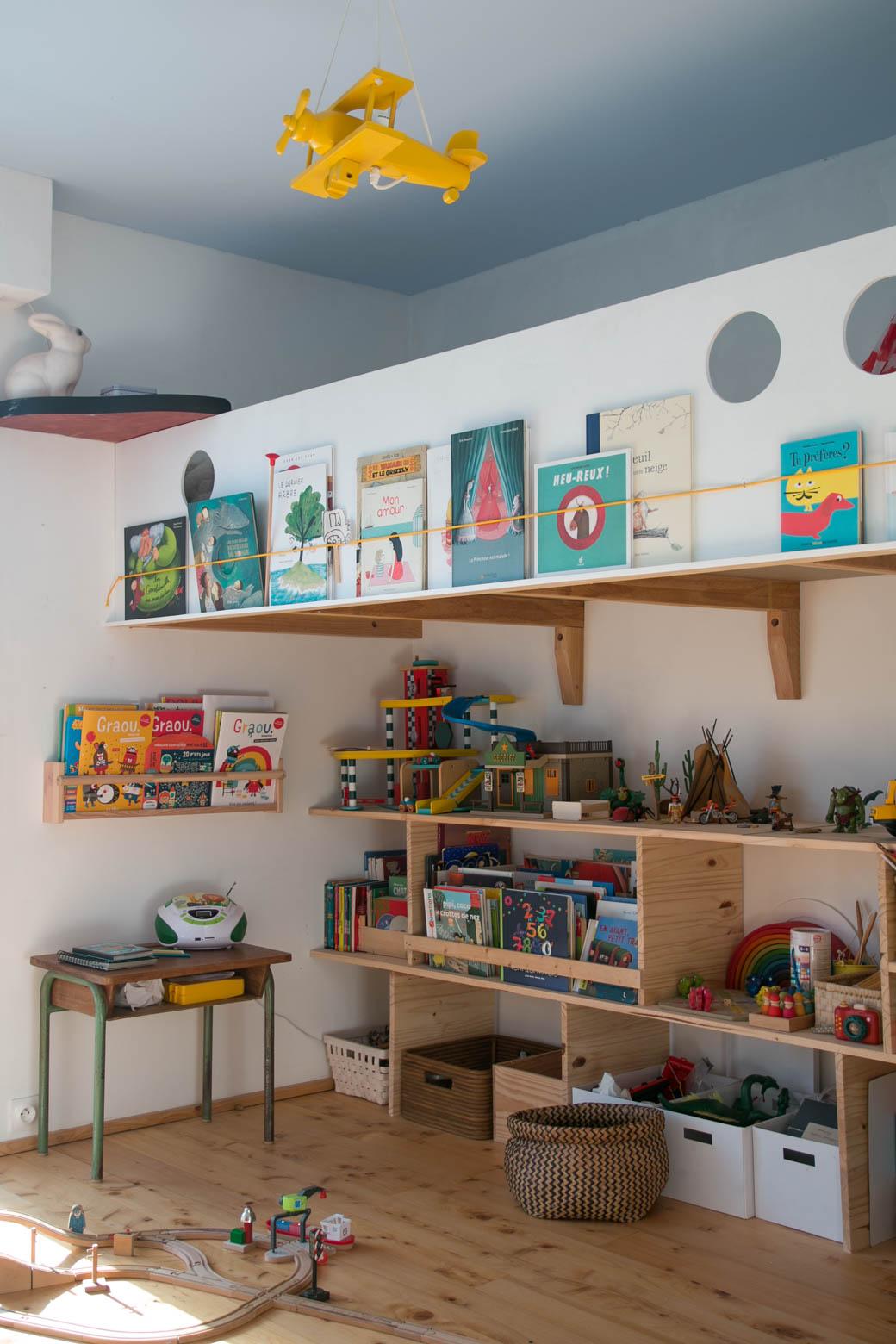Vue générale sur la chambre de Lulu. Une mezzanine a été construite de part et d'autre du mur. Pour y dormir, y jouer aux pirates et lire. Dessous, il y a beaucoup de rangements pour les jouets et les livres. Le plafond est bleu, la lampe est un lapin et un oisieau. Jérôme Barrier. Meuble sur mesure. Vertou Nantes Loire atlantique