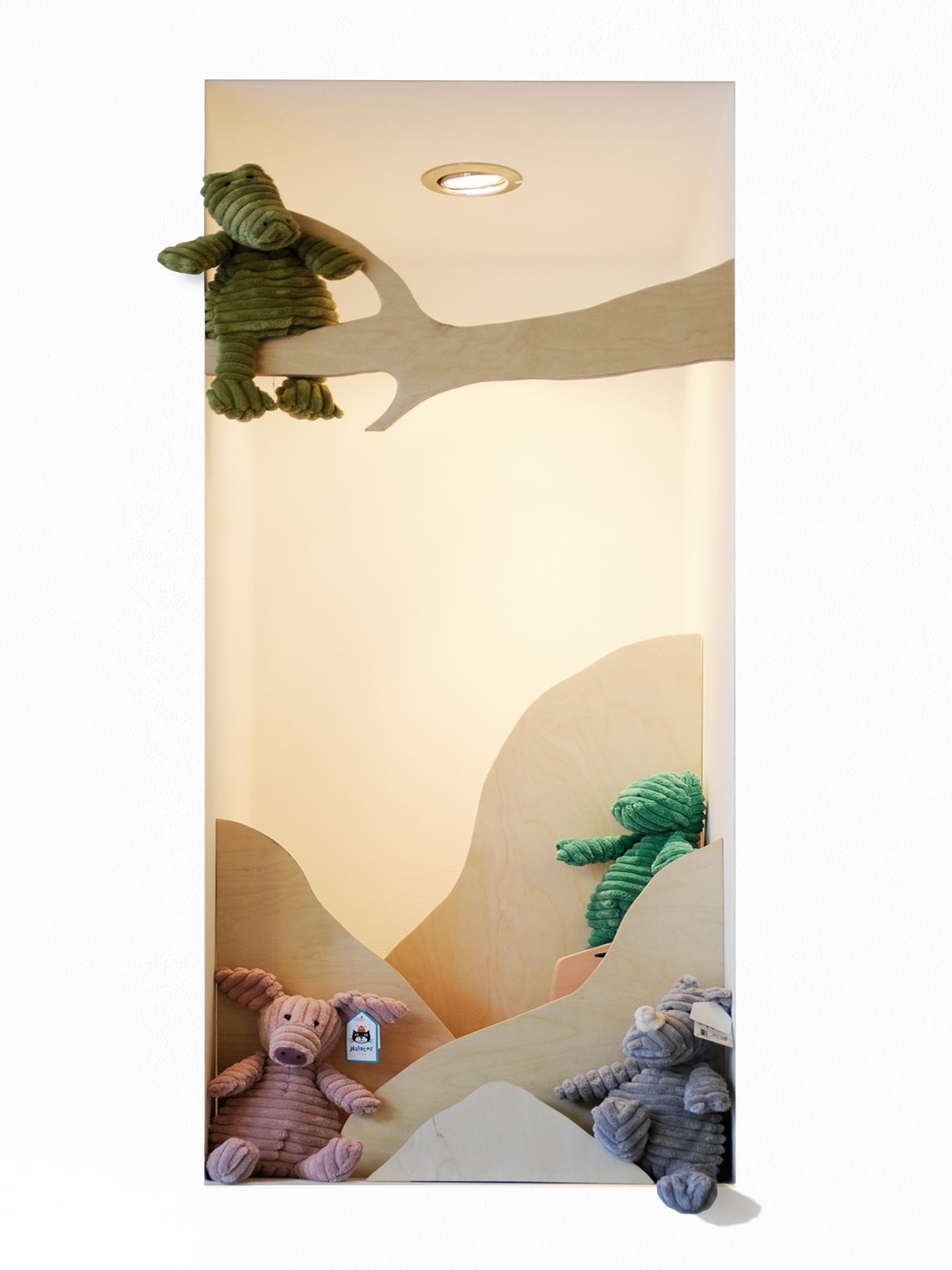 Une niche aménagée avec des éléments en multiplis de bouleau composant un paysage avec des personnages et des peluches.